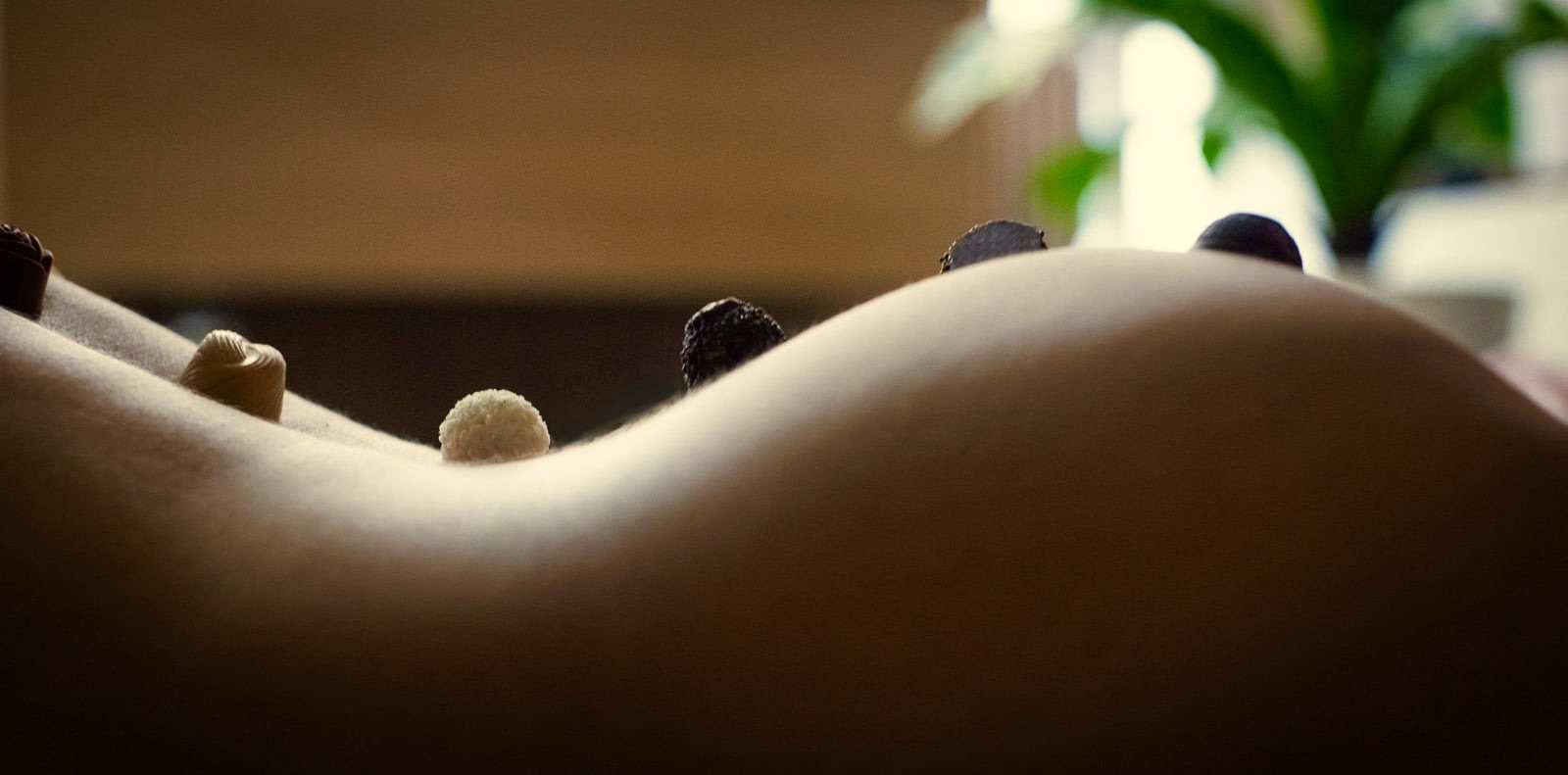 Csábító női idomok, csokoládé, halvány meleg fények