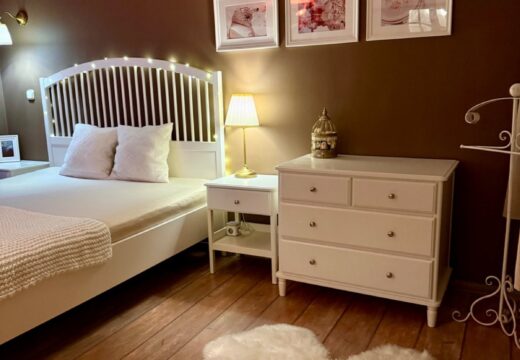 Fehér franciaágy, komód és klíma a Romantik apartman barna falú hálóterében.
