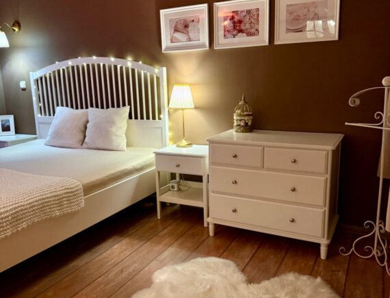 Fehér franciaágy, komód és klíma a Romantik apartman barna falú hálóterében.