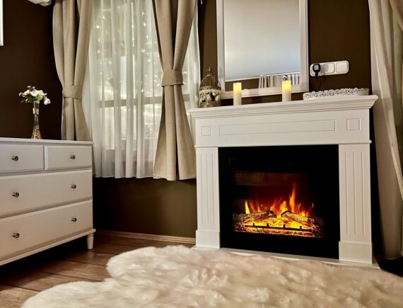 Fehér látványkandalló tükörrel, gyertyákkal és puha szőnyeggel a Romantik apartmanban.